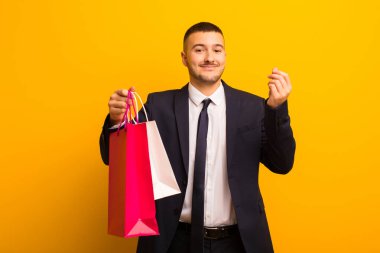 Genç ve yakışıklı iş adamı, arka planda alışveriş torbalarıyla.