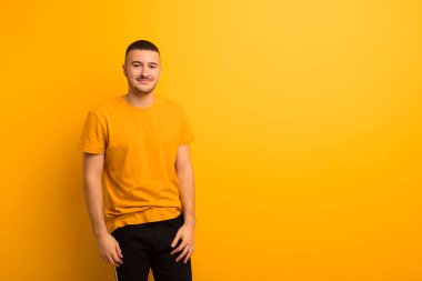 Genç yakışıklı adam pozitif ve kendinden emin gülümsüyor. Tatmin olmuş, arkadaş canlısı ve mutlu görünüyor.