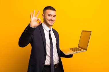 Genç ve yakışıklı bir iş adamı dizüstü bilgisayar tutuyor.