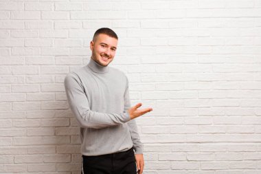Genç yakışıklı adam neşeyle gülümsüyor, mutlu hissediyor ve fotokopi uzayında bir konsept gösteriyor.
