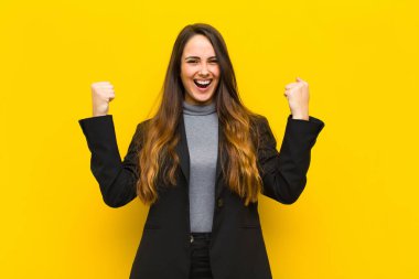 Genç, güzel bir kadın mutlu, şaşırmış ve gururlu hissediyor, bağırıyor ve başarıyı büyük bir gülümseme işi veya iş konseptiyle kutluyor.