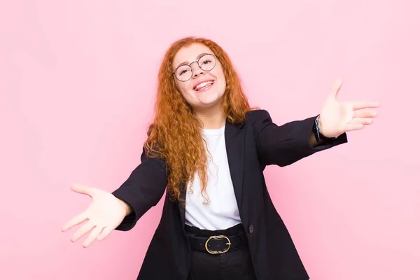 young red head woman smiling cheerfully giving a warm, friendly, loving welcome hug, feeling happy and adorable against pink wall