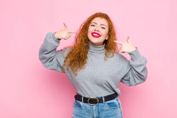 Junge Rote Kopffrau Lächelt Selbstbewusst Und Zeigt Auf Ihr Eigenes — Stockfoto