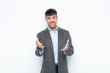 Genç yakışıklı adam kendini mutlu, şaşkın, şanslı ve şaşırmış hissediyor. Beyaz duvara karşı inanılmaz.