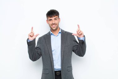 Genç yakışıklı bir adam kendi gülüşünü çiziyor, iki eliyle, pozitif ve mutlu görünüyor, sağIık kavramı beyaz duvara karşı.