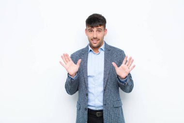 Genç yakışıklı adam gergin, endişeli ve endişeli görünüyor, benim hatam olmadığını söylüyor, yoksa beyaz duvara karşı yapmazdım. 