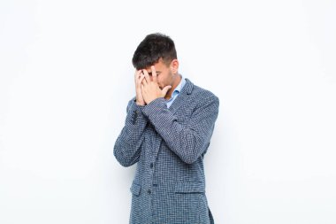 Genç yakışıklı adam, üzgün, hayal kırıklığına uğramış bakışlarıyla gözlerini kapıyor. Ağlıyor, beyaz duvara yan bakıyor.