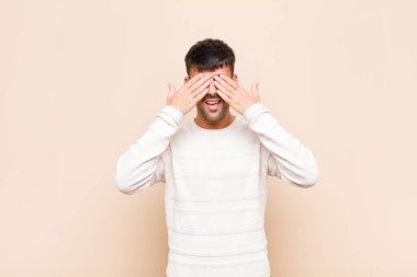 Genç yakışıklı adam gülümsüyor ve mutlu hissediyor, iki eliyle gözlerini kapatıyor ve sıcak duvara karşı inanılmaz bir sürpriz bekliyor.