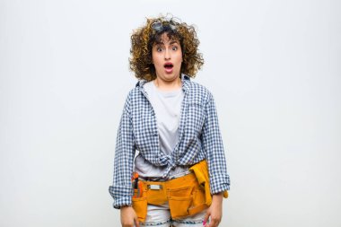 Genç hizmetçi kadın korkmuş ve şok olmuş hissediyor, ağzı açık beyaz duvara karşı şaşkınlık içinde.