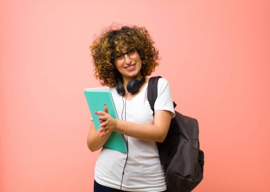 Genç ve güzel bayan öğrenci kendini mutlu ve başarılı hissediyor, gülümsüyor ve alkışlıyor, pembe duvara karşı alkış ile tebrik ediyor.