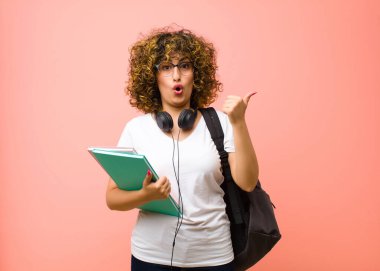 Genç, güzel bir bayan öğrenci, inançsızlıktan şaşkın şaşkın bakıyor, yan taraftaki objeyi işaret ediyor ve 