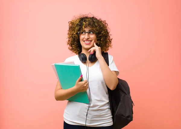 若い可愛い学生の女性は ピンクの壁に反対側を見て喜びと空想や疑問を笑っています — ストック写真