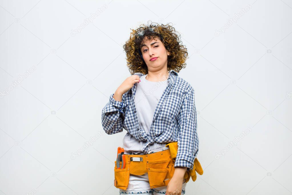 young housekeeper woman looking arrogant, successful, positive and proud, pointing to self against white wall