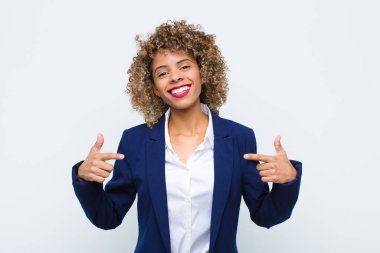 Genç Afrikalı Amerikalı gururlu, kibirli, mutlu, şaşırmış ve tatmin olmuş görünüyor. Kendini göstererek düz duvara karşı kazanan gibi hissediyor.