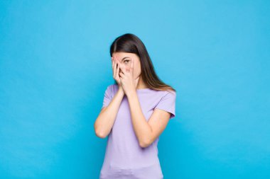 Genç, güzel bir kadın korkmuş ya da utanmış hissediyor. Gözleri yarı kapalı mavi duvara bakıyor ya da dikizliyor.