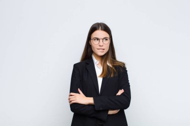 Genç iş kadını kuşkulanıyor ya da düşünüyor, dudağını ısırıyor ve gergin hissediyor, beyaz duvara karşı boşluğu kopyalamak istiyor.