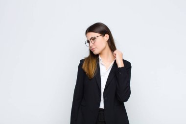 Genç iş kadını stresli, endişeli, yorgun ve hayal kırıklığına uğramış, gömleğini çekmiş, beyaz duvara karşı sorunlu görünüyor.