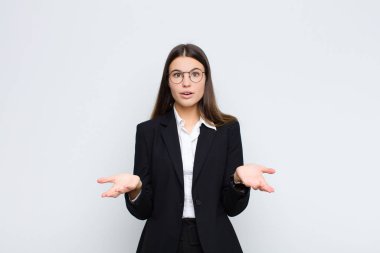 Genç iş kadını beyaz duvara karşı inanılmaz bir sürprizle şaşkın ve hayretler içinde kaldı.