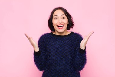 Genç, güzel bir kadın mutlu, heyecanlı, şaşırmış ya da şok olmuş hissediyor. Gülümsüyor ve hayrete düşüyor.