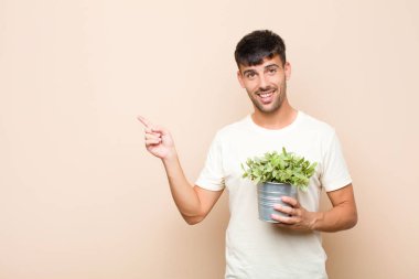 Genç ve yakışıklı bir adam heyecanlı ve şaşırmış görünüyor. Bir bitkiyi elinde tutarak uzayın kenarını ve yukarısını gösteriyor.