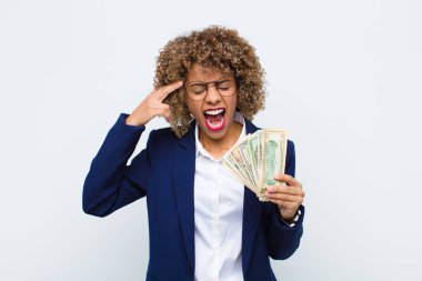 Genç Afro-Amerikan kadın mutsuz ve stresli görünüyor, intihar jesti silahla işaret ediyor, Euro banknotlarını işaret ediyor.