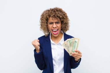 Genç Afrikalı Amerikalı kadın öfkeli bir ifadeyle ya da yumruklarıyla bağırarak başarıyı avro banknotlarıyla kutluyor.
