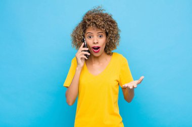 Genç afro-amerikan duyguları şok olmuş ve şaşırmış, endişeli ve paniklemiş, stresli ve dehşete düşmüş bir şekilde bir cep telefonuyla bakıyor.