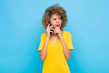 Genç Afro-Amerikan düşünceleri, kuşkulu ve kafası karışık, farklı seçenekleri olan, cep telefonuyla hangi kararı vereceğimi merak eden