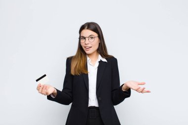 Genç ve güzel bir kadın son derece şaşırmış, endişeli ve paniklemiş hissediyor, stresli ve dehşete düşmüş bir şekilde kredi kartıyla bakıyor.