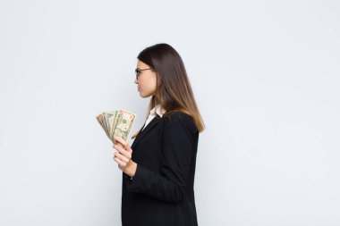 Profil görünümünde genç, güzel bir kadın ilerideki boşluğu kopyalamak istiyor. Düşünüyor, hayal ediyor ya da banknotlarla hayal ediyor.