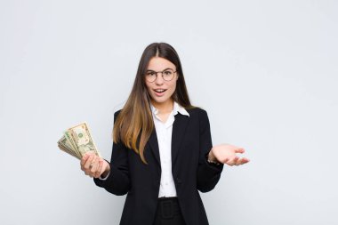 Genç, güzel bir kadın şok olmuş ve şaşırmış, endişeli ve paniklemiş, stresli ve dehşete düşmüş bir şekilde banknotlarla bakıyor.