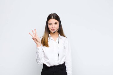 Genç, güzel bir kadın gülümsüyor ve arkadaş canlısı görünüyor. Elleri önde, kulaklıkları ve mikrofonuyla geriye doğru sayıyor.