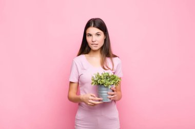 Genç ve güzel bir kadın şaşkın ve şaşkın görünüyor, gergin bir hareketle dudağını ısırıyor, bitkiyle ilgili sorunun cevabını bilmiyor.