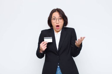 Genç ve güzel bir kadın son derece şaşırmış, endişeli ve paniklemiş hissediyor, stresli ve dehşete düşmüş bir şekilde kredi kartıyla bakıyor.