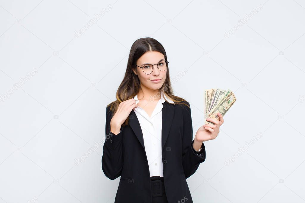 young pretty woman looking arrogant, successful, positive and proud, pointing to self with banknotes