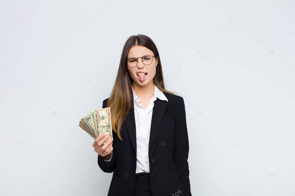 young pretty woman feeling disgusted and irritated, sticking tongue out, disliking something nasty and yucky with banknotes