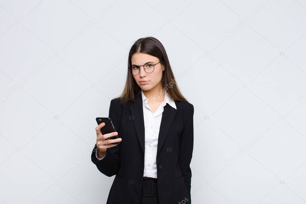 young pretty woman feeling sad and whiney with an unhappy look, crying with a negative and frustrated attitude with a mobile phone
