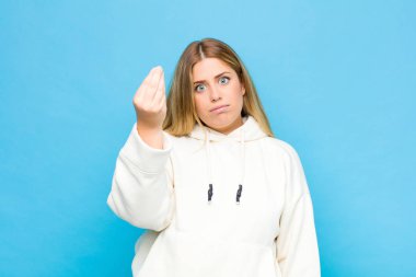 Genç sarışın kadın kapiş ya da para hareketi yapıyor, sana borçlarını ödemeni söylüyor! yassı duvara karşı