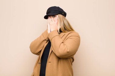 Genç sarışın kadın korkmuş ya da utanmış hissediyordu, dikizliyordu ya da gözleri yarı çıplak bir şekilde duvara bakıyordu.