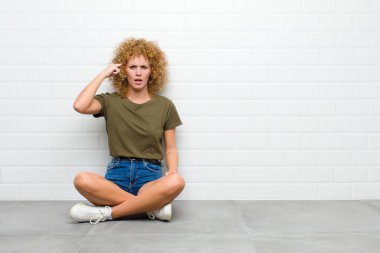 Genç afro kadın şaşkın ve şaşkın hissediyor, sana deli, deli ya da aklını kaçırmış olduğunu gösteriyor.