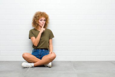 Genç afro kadın sessizlik ve sessizlik istiyor, parmaklarıyla ağzının önünde işaret ediyor, 