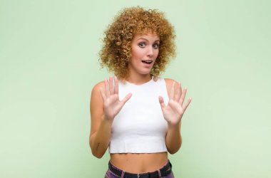 Genç afro kadın gergin, endişeli ve endişeli görünüyor, benim hatam olmadığını yoksa yeşil duvara karşı yapmayacağımı söylüyor.