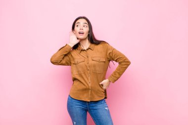 Genç, güzel bir kadın gülümsüyor, tuhaf bir şekilde yan tarafa bakıyor, dedikoduları dinlemeye çalışıyor ya da pembe duvara karşı bir sırrı duymaya çalışıyor.