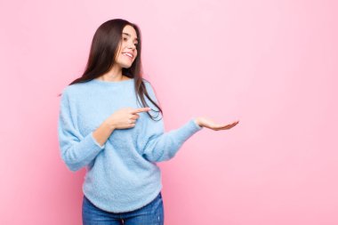 Genç, güzel bir kadın gülümsüyor, mutlu, kaygısız ve tatmin olmuş hissediyor. Fotokopi odasının kenarındaki pembe duvara işaret ediyor.