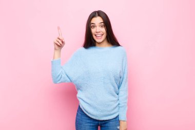 Genç ve güzel bir kadın bir fikri fark ettikten sonra mutlu ve heyecanlı bir dahi gibi hissediyor, neşeli bir şekilde parmağını kaldırıyor, eureka! Pembe duvara yaslan