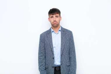 Genç yakışıklı adam üzgün ve mızmız, mutsuz bir bakışla ağlıyordu. Beyaz duvara karşı olumsuz ve hayal kırıklığına uğramış bir tavır içindeydi.