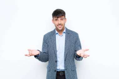 Genç, yakışıklı bir adam kendini cahil ve kafası karışık hissediyor. Hangi seçeneği seçeceğinden emin değil. Beyaz duvara karşı merak içinde.