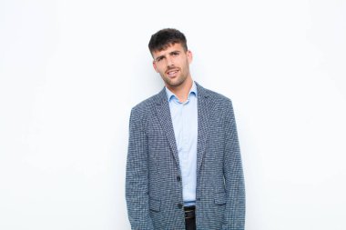 Genç yakışıklı adam şaşkın ve şaşkın hissediyor, aptal, afallamış bir ifadeyle beklenmedik bir şeye bakıyor beyaz duvara karşı.