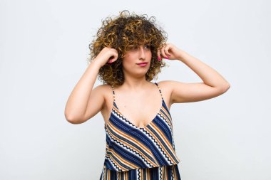 Genç, güzel bir kadın, kafası karışmış ya da şüpheye düşmüş, bir fikre odaklanmış, çok düşünüyor, beyaz duvara karşı uzayı kopyalamak istiyor.