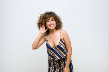 Genç, güzel bir kadın gülümsüyor, tuhaf bir şekilde yan tarafa bakıyor, dedikoduları dinlemeye çalışıyor ya da beyaz duvara karşı bir sırrı duymaya çalışıyor.